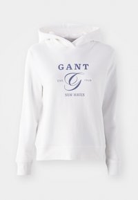 Bílá mikina s kapucí vyrobená z měkké bavlny, s potiskem loga na přední straně v námořnické modři s textem "GANT EST. 1949 NEW HAVEN." Standardní střih a dlouhé rukávy.