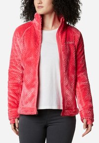 Giacca in pile di un luminoso rosa, con un motivo testurizzato, zip frontale completa e polsini a coste. Fodera interna liscia senza loghi visibili.