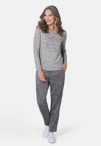 Graues Langarmoberteil mit strukturiertem Muster; graue Hose mit Reißverschlüssen; weiße Sneakers; glatter Stoff, lässige Passform, modernes Design.