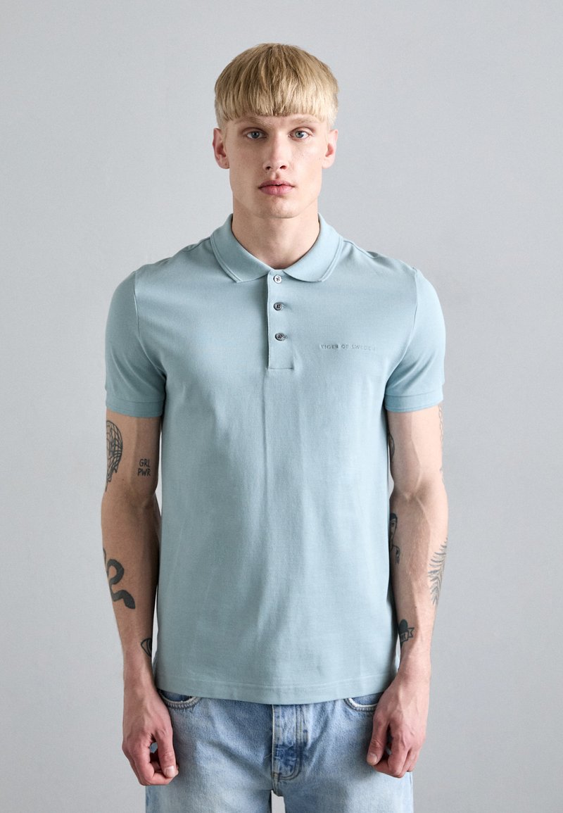 Svetlo modra polo majica iz bombaža, s tremi gumbi in kratkimi rokavi ter diskretnim logotipom na prsih.