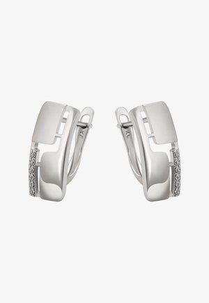 Pár stříbrných zavěšených kruhových náušnic s řadou malých průhledných drahokamů na jednom okraji na bílém pozadí.