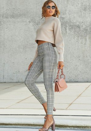 Beige cropped sweater, gray checkered high-waisted pants, pink handbag with chain handle, and heeled sandals with ankle strap.