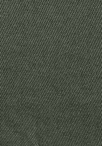 Tissu vert olive avec une texture de tissage fin et uniforme. Les détails des fils visibles créent une apparence lisse, adaptée aux vêtements ou à l'ameublement.