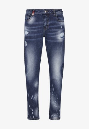 Sinised kitsaste säärega teksapüksid kulunud alade ja pleekimistega reitel, põlvedel ja sääre ülaosas, esitaskute ja vööaasadega.