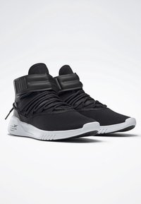 Svarta träningsskor med överdel i mesh, vadderad tunga och en strömlinjeformad design. Vit gummisula med spår för grepp och stabilitet.