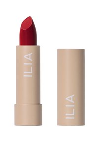 Röd läppstift i kulform, förpackad i ett beige rör med vit branding. Slät textur, elegant design och inga synliga mönster.