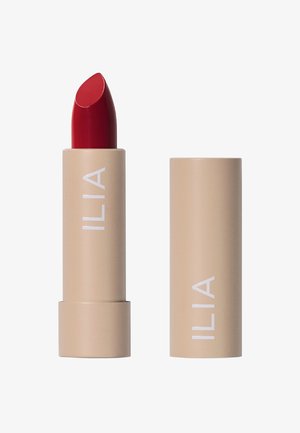 Rouge à lèvres de couleur rouge, en forme de balle, logé dans un tube beige portant une marque blanche. Texture lisse, design épuré et sans motifs visibles.