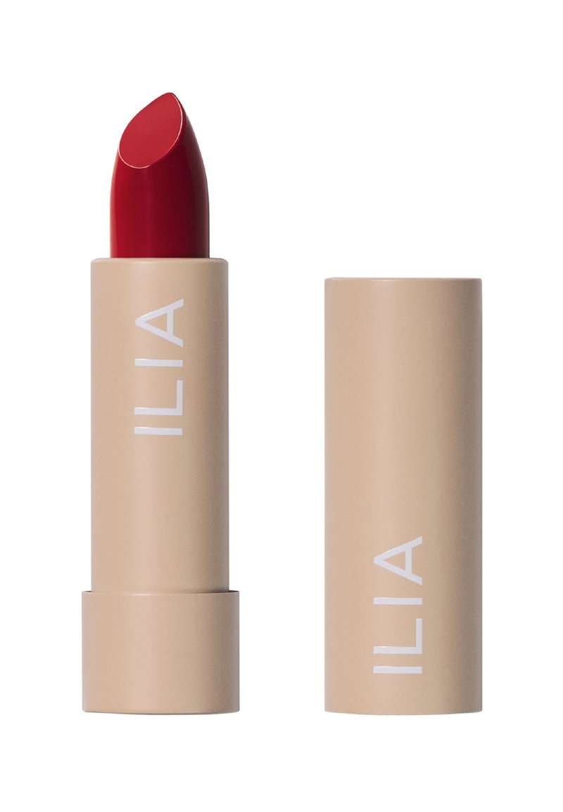 Röd läppstift i kulform, förpackad i ett beige rör med vit branding. Slät textur, elegant design och inga synliga mönster.