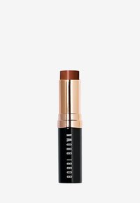 Leppefarge stick med sylindrisk form. Mørkebrun topp og blankt gull- og svart etui. Merket viser "BOBBI BROWN" i hvitt.