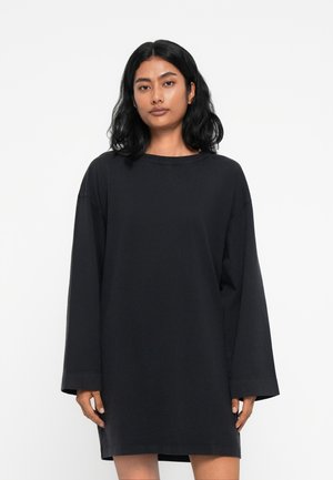 Čierne oversized šaty s dlhými rukávmi, okrúhlym výstrihom a mäkkou bavlnenou textúrou. Minimalistický dizajn, žiadne viditeľné vzory alebo hardvér.