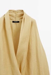 Beige Leinen-Wickeloberteil mit tiefem V-Ausschnitt, drapiertem Silhouette und einem Etikett mit "Massimo Dutti"-Label hinten.