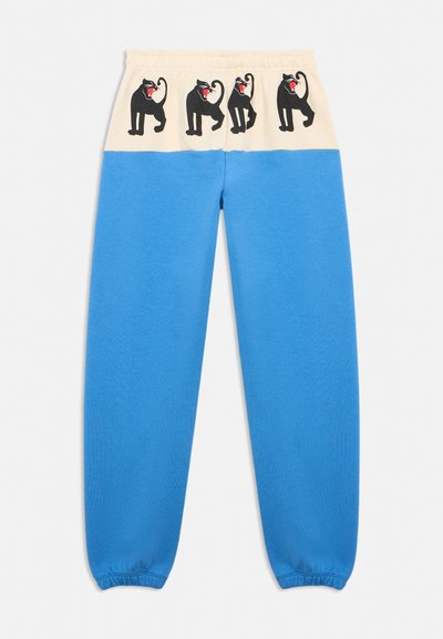 Blue sweatpants with beige waistband featuring four black panther illustrations with red mouths along the top.