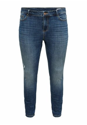 Jean denim bleu slim avec légère décoloration et une petite zone usée sur la cuisse gauche, doté de poches avant et d'une fermeture à boutons.