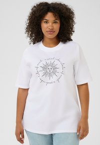 T-shirt en coton blanc avec un graphique de soleil noir et du texte, à manches courtes, col rond, et coupe décontractée. Le texte indique : "un bon état d'esprit."