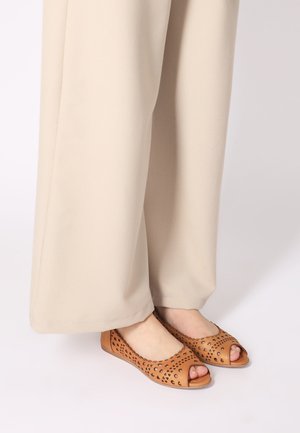 Tan peep-toe flats met snedeontwerp, gemaakt van leer. Heeft een gladde afwerking en een ronde neus. Gemaakt met beige wijde broek.