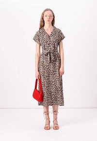 Rochie midi cu imprimeu de leopard, cu mâneci scurte, talie cu curea și buzunare laterale. Complementată cu o poșetă roșie și sandale bej cu șireturi.