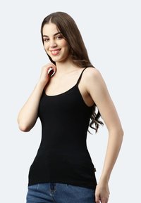 Schwarzes Tanktop mit dünnen Trägern, figurbetontem Design, glatter Textur und leichtem Stretch, kombiniert mit blauen Jeansshorts.