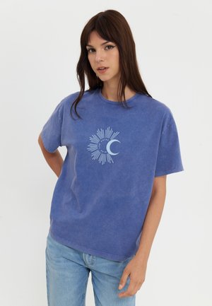 T-shirt en coton bleu à manches courtes avec un motif soleil et lune bleu clair. Coupe décontractée avec une surface légèrement texturée.