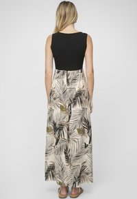 Robe maxi avec un haut noir ajusté et une jupe fluide à motifs de feuilles de palmier dans des tons de vert et de beige. Tissu texturé.