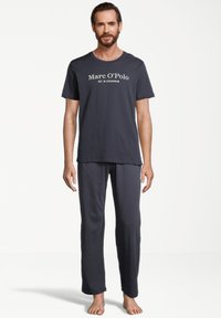 Mørkegrå pyjamas sæt med en kortærmet t-shirt med hvid "Marc O'Polo" tekst og matchende lange bukser lavet af blødt stof.