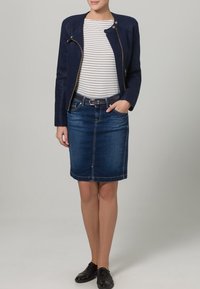 Marineblaue Jacke mit Reißverschluss, gestreiftes Oberteil in Weiß und Marineblau, blauer Jeans-Bleistiftrock, schwarze Schuhe; elegantes, tailliertes Design mit minimaler Hardware.