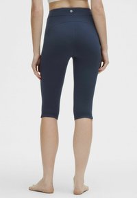 Navy knee-length athletic leggings with a high waistband, featuring smooth, stretchy fabric and a logo detail on the back.