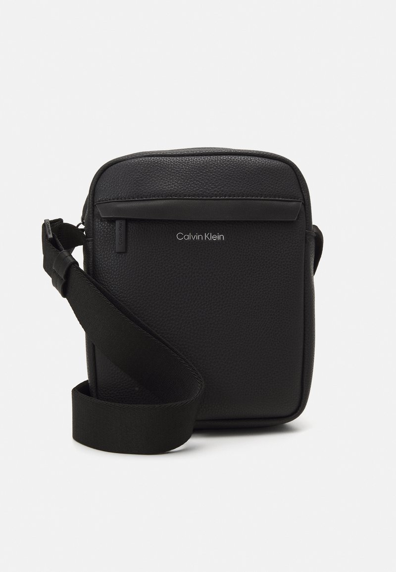Borsa a tracolla rettangolare nera in pelle texturizzata, con tasca frontale con zip, tracolla regolabile e logo impresso.