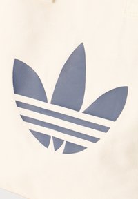 Λογότυπο μπλε τριφυλλιού με τρεις οριζόντιες ρίγες σε επιφάνεια από υποκίτρινο ύφασμα.