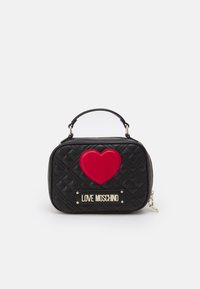 Svart quiltad handväska med övre handtag, röd hjärtdekal och guldig "Love Moschino" logoplatta framtill.