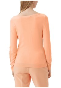 Pull en maille de couleur pêche avec manches longues, un large décolleté et un ourlet côtelé. Texture lisse avec une silhouette ajustée.