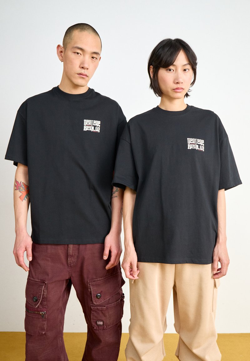 Black cotton t-shirts with a small white graphic on the chest, paired with contrasting cargo pants in maroon and beige.