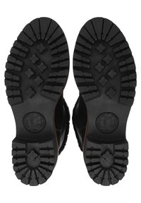 Suelas de botas de goma negra con un patrón de dibujo profundo. Presenta áreas de agarre elevadas en forma de diamante y un logo de la marca embossado en el talón.