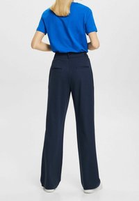 Niebieska bawełniana koszulka zestawiona z wysokim stanem, szerokimi spodniami w kolorze granatowym, które mają dwie tylne kieszenie i gładkie wykończenie materiału.