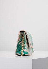 Green palm leaf print handbag with a structured design, pink accents, gold chain strap, and a magnetic closure on the front.