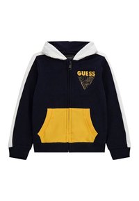 Sudadera con cremallera de color azul marino, con capucha blanca y rayas en las mangas, bolsillos frontales amarillos y logo de "GUESS" en amarillo en el pecho.