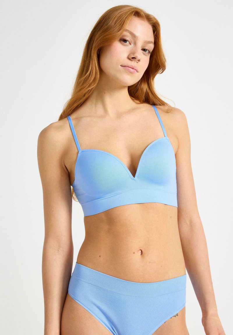 Vaaleansininen saumaton bralette, jossa on syvä kaula-aukko, ohuet säädettävät olkaimet ja sileä, joustava kangas. Yhdistetty yhteensopiviin ribbikuituisiin alusvaatteisiin.