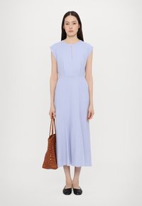 Rochie midi de un violet deschis cu mâneci scurte, detaliu cu gât în formă de cheie la decolteu și o textură netedă; asortată cu o geantă tote din piele perforată de culoare maro și pantofi negri.