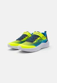 Baskets gris et jaune fluo avec des accents bleus. Présentent un dessus en maille, une semelle rembourrée et des lacets élastiques. Marque sur la sangle et sur la languette.
