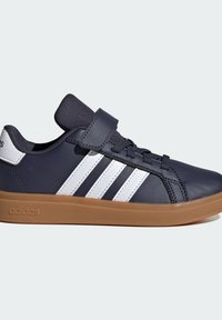 Zapatilla azul marino con rayas blancas, que presenta una parte superior de cuero, lengüeta de tela texturizada, cierre de cordones y velcro, y suela de goma.