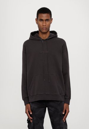 Dark gray hoodie made of cotton blend, featuring a kangaroo pocket, drawstring hood, and embroidered logo on the chest. Worn with camo pants.