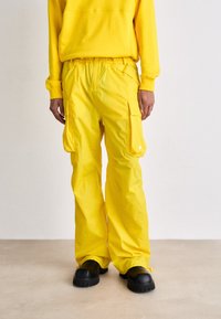 Geel cargobroek gemaakt van een gladde, lichte stof, met zijzakken, een elastische tailleband en een losse, comfortabele pasvorm.