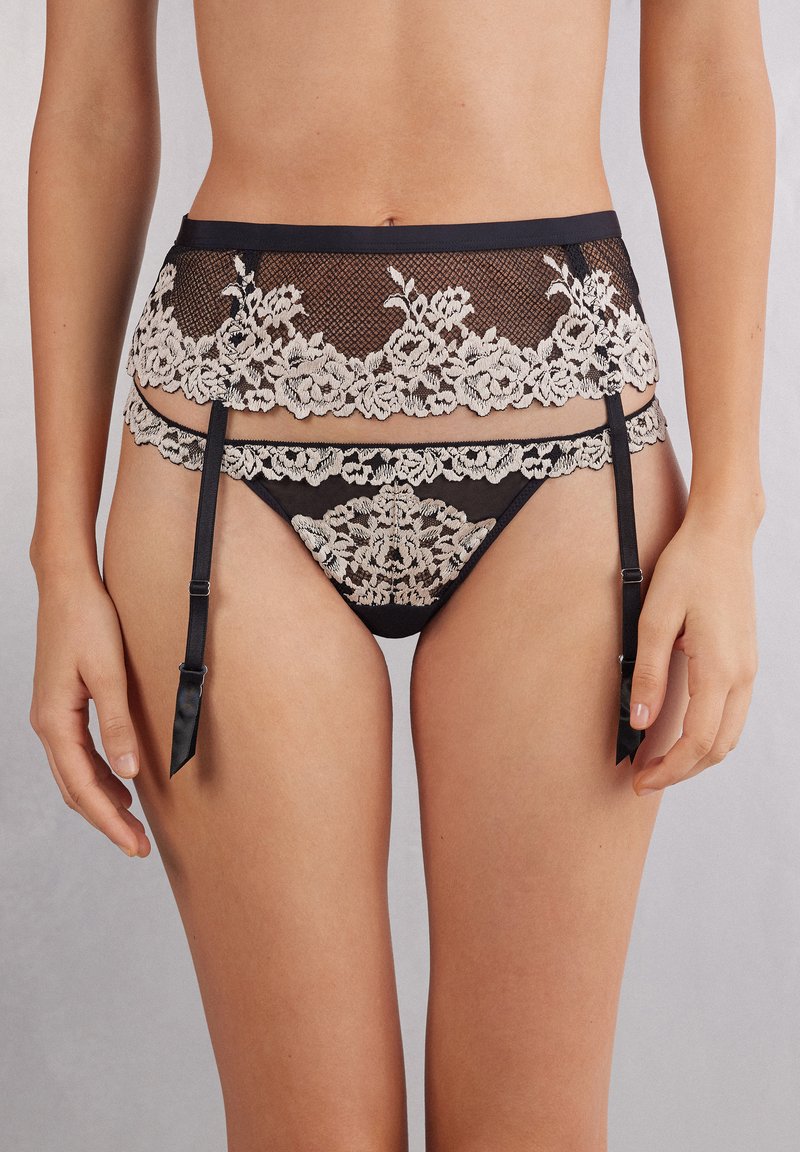 Sort blonde-strumpebælte med cremegul blomsterbroderi, parret med matchende nettrusse. Indeholder justerbare sorte satinbånd og blomsterdetaljer.