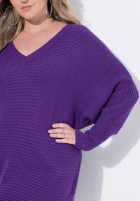 Jersey morado texturizado de punto con cuello en V y corte oversize, con mangas amplias y acentos acanalados en los puños, que presenta una silueta relajada.