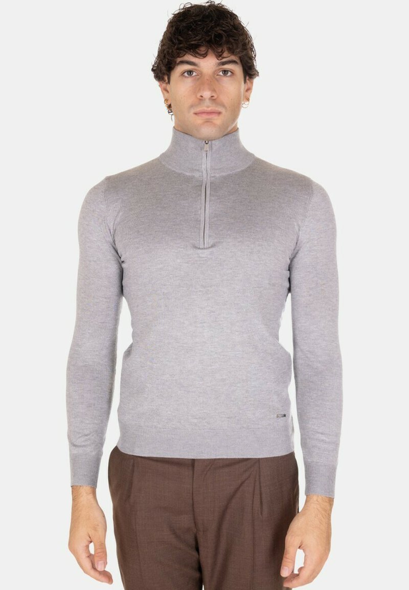 Maglione grigio a maniche lunghe con chiusura a zip, realizzato in un tessuto a maglia fine e liscio. Presenta un design aderente e polsini a coste sui polsi.