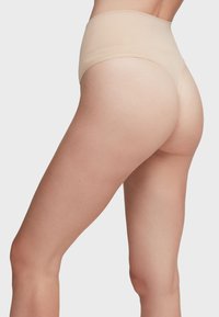 Culotte taille haute beige sans couture avec une texture lisse et un design arrière arrondi, offrant un ajustement confortable et une couverture minimale.