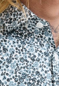 Camicia di tessuto leggero con stampa floreale in tonalità di blu e nero, con colletto button-down e bottoni bianchi.