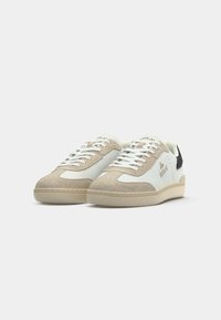 Baskets basses en suède blanches et beige avec lacets blancs et logo "REPLAY" sur le côté et la languette, présentées sur un fond blanc.