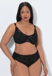 Mustavalaiseinen bralette, jossa on ristikkäinen muotoilu ja säädettävät olkaimet. Yhteensopivat korkeavyötäröiset pitsi-alushousut, joissa on kukkakuvio ja puolikiiltävä rakenne.