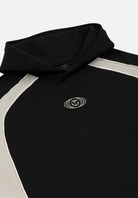 Zwarte hoodie met een grijze accentstreep, een ronde logo patch met een embleem en een zachte textuur. Heeft een capuchon met koordjes en naden.