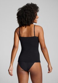 Black cotton tank top with thin straps, fitted design, and a smooth texture. Worn with matching black brief. Back view displayed.